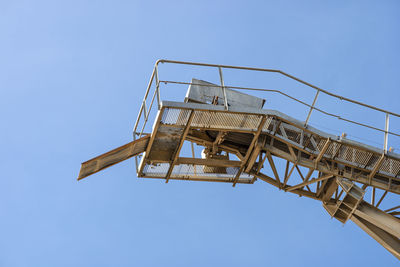 Conveyor belt for gravel against the blue sky at an industrial cement plant.