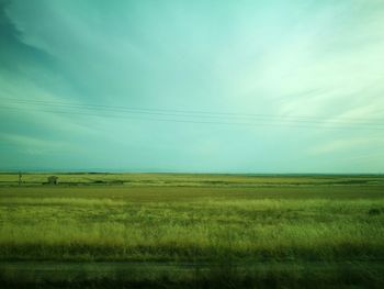 Scenic view of grassy field against cloudy sky