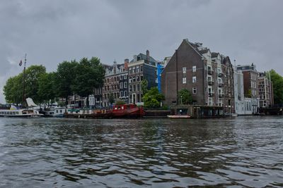 Buildings by river against sky