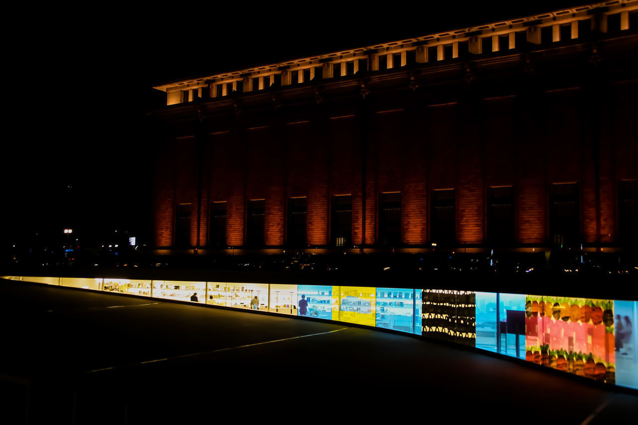 ILLUMINATED BUILDING BY STREET AT NIGHT