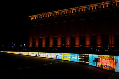 Illuminated building by street in city at night