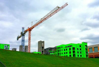 Low angle view of crane against cloudy sky