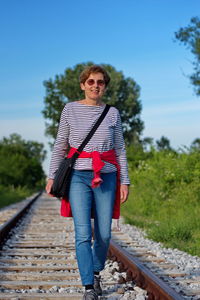 Front view of senior woman walking along reilroad tracks