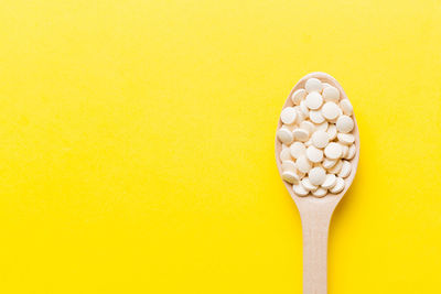 Directly above shot of pills on yellow background