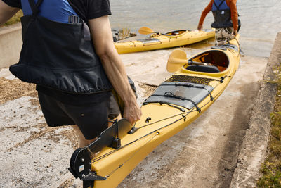 High angle view of men carrying kayak at coast