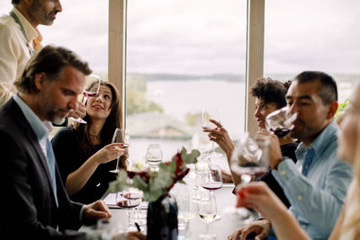 Male and female colleagues with red wine at table during kick off meeting in convention center