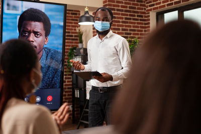 Portrait of businessman wearing mask giving presentation at office