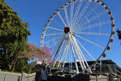 Low angle view of ferris wheel against clear blue sky