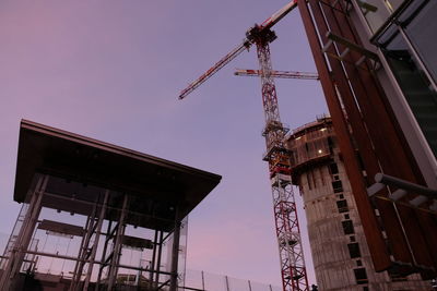 Low angle view of crane at construction site against sky