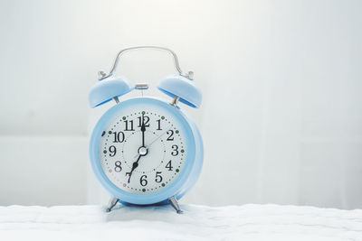 Close-up of alarm clock on bed against wall