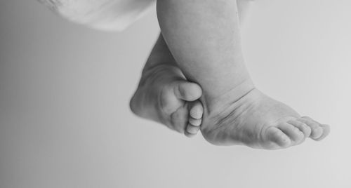 Low section of baby lying on white background