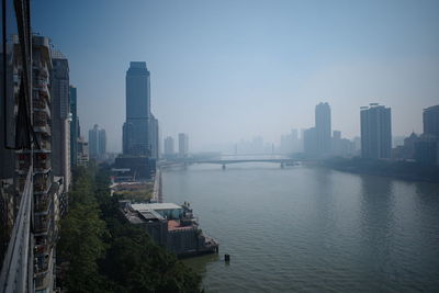 Buildings by river against sky in city