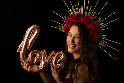 Portrait of smiling young woman against black background