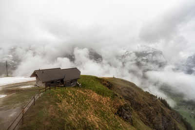 A small hut on top of grindelwald first snow covered summit. mountain and hill tops covered in snow