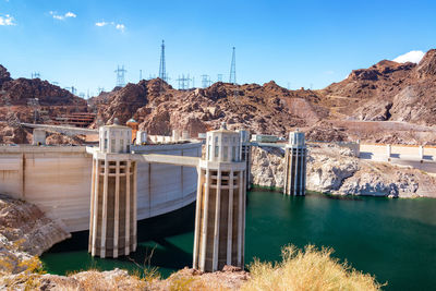 Dam by river and mountains against sky