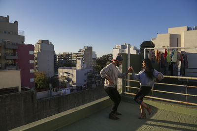 People walking on buildings in city against clear sky