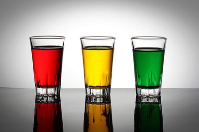 Glasses of beer on table against white background