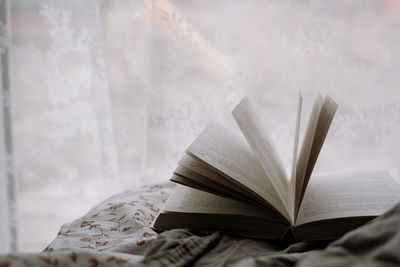 Close-up of open book on bed