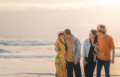 Cheerful family standing on beach during sunset