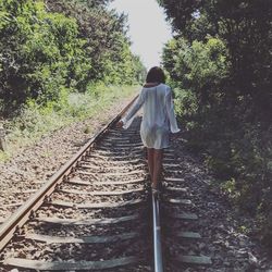 Rear view of woman walking on railroad track