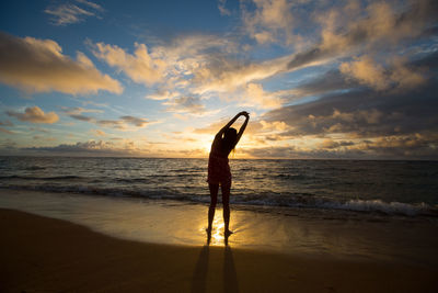 Silhouette of woman on beach against sunset sky