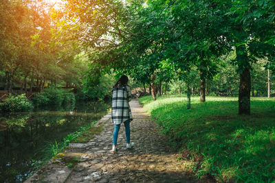 Rear view of woman walking on footpath in park