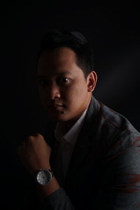 Portrait of young businessman against black background