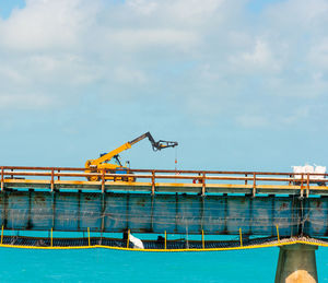 Low angle view of crane at swimming pool against sky