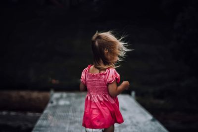 Close-up of girl standing against black background