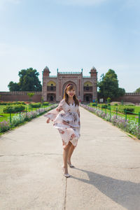 Full length of smiling young woman against the sky