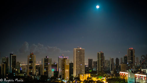 Illuminated cityscape against sky at night