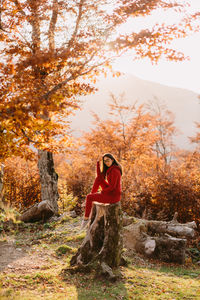 Woman standing by tree in forest during autumn