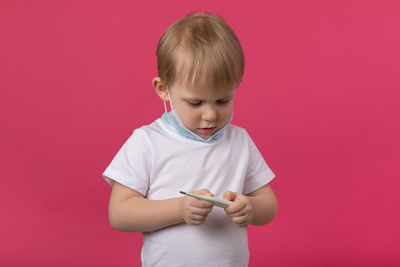 A young child doctor with a medical mask holds a thermometer in his hands and looking. 