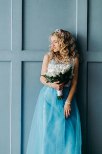 Midsection of woman wearing blue dress holding bouquet