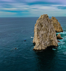 Rock formation in sea against sky