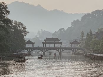 Scenic view of river by houses against sky