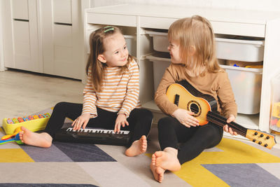Happy children playing musical instruments at home. sisters have fun in the room