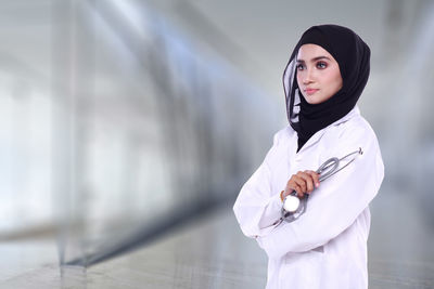 Female doctor standing against wall