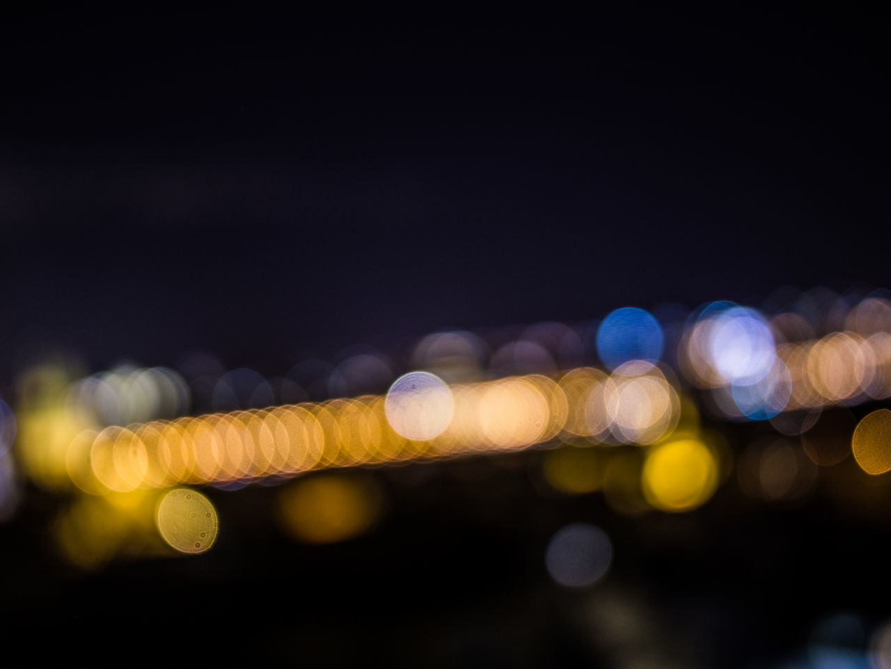 DEFOCUSED IMAGE OF ILLUMINATED LIGHTS ON STREET AT NIGHT