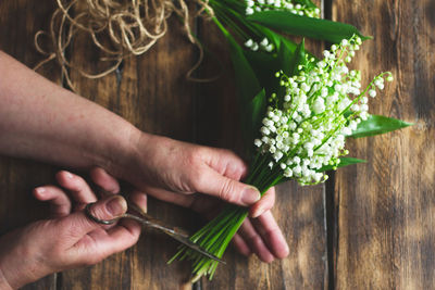 Midsection of man holding flower bouquet on table