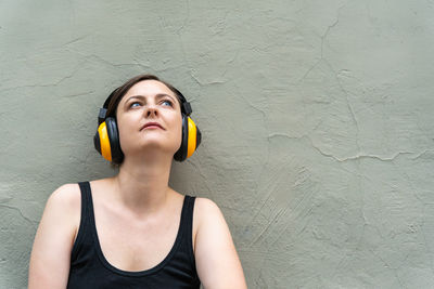 Portrait of young woman standing against wall
