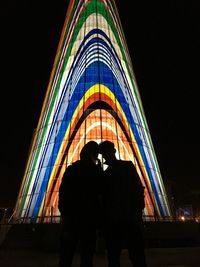 Low angle view of silhouette people standing against illuminated lights at night