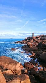 Distant view of lighthouse by sea against sky