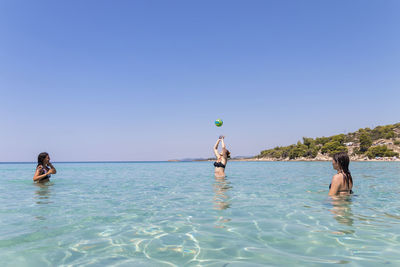 Happy teenagers playing volleyball in water at the vacation and fun