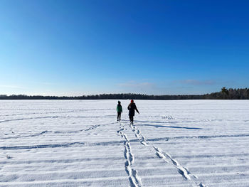 People on snow covered landscape against blue sky