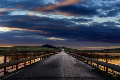Empty road against cloudy sky during sunset