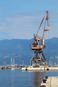 Cranes at harbor against sky