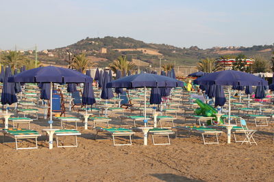 Chairs and tables on beach against sky