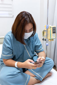 Illness asian patient women using mobile phone for checking social media in patient room of hospital