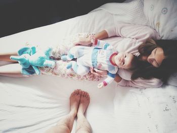 Low section of man standing by woman and baby boy on bed at home